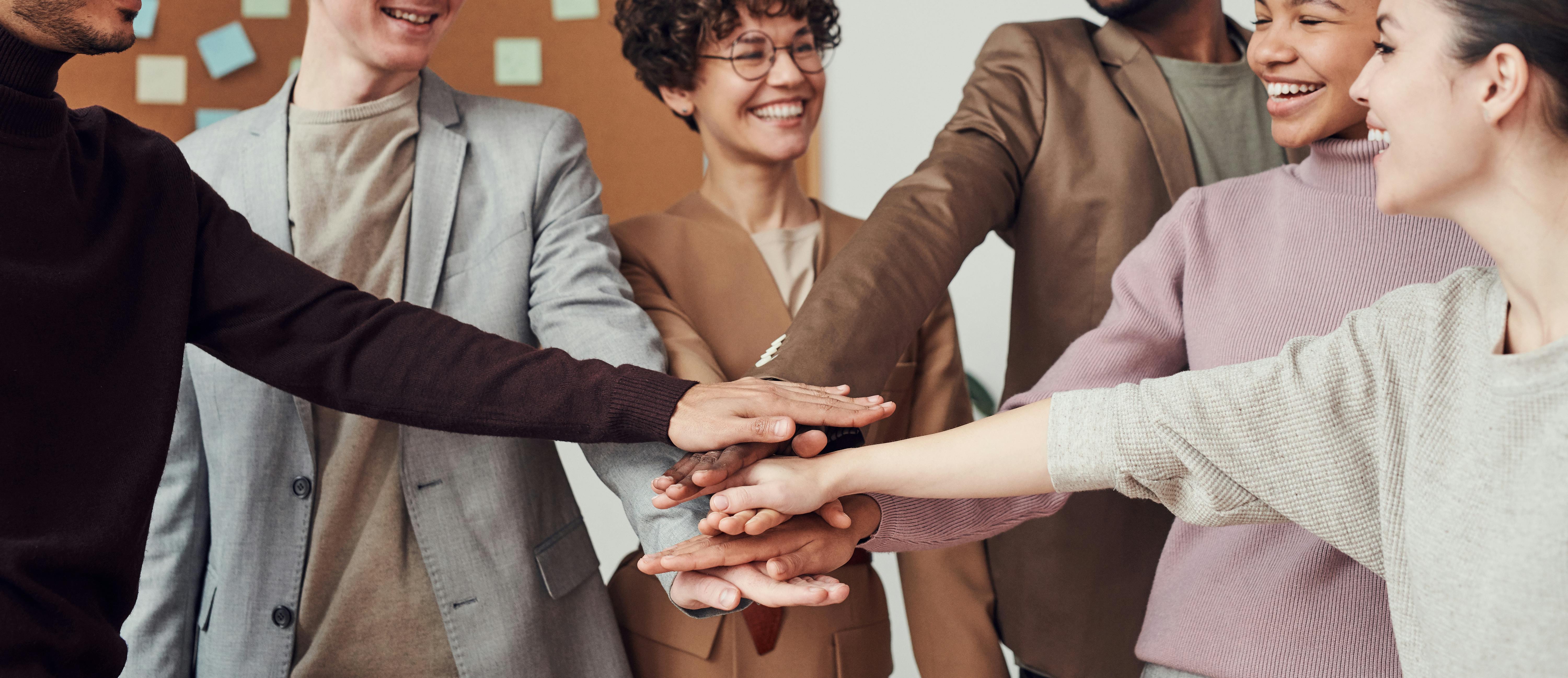 Group of diverse individuals putting hands together in a stack.