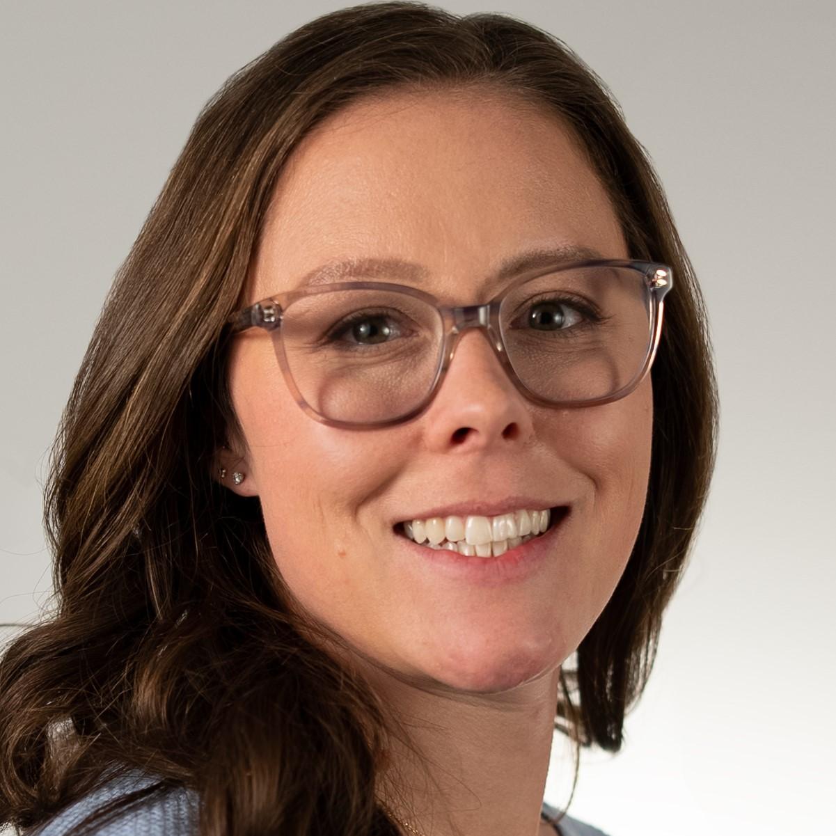 Courtney Phillips headshot: woman with long brown hair and glasses.