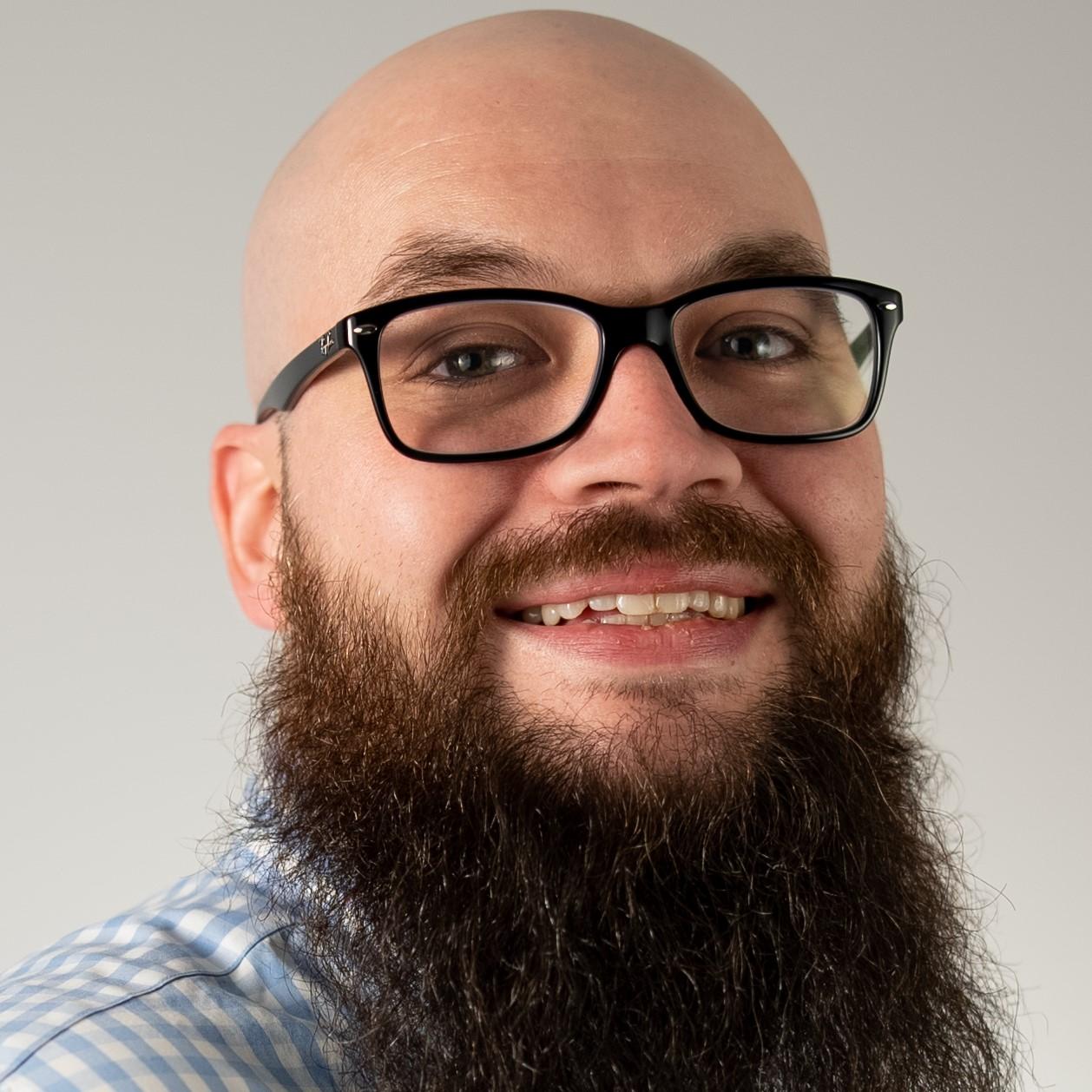 Drew Grissom headshot: bald male with black rimmed glasses and long beard.