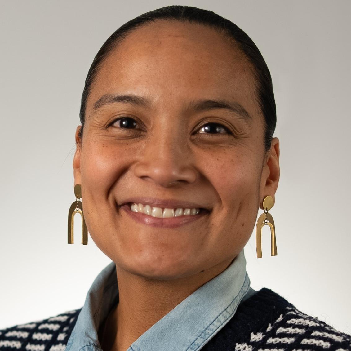 Joanne Sax headshot: smiling woman with hair pulled back and gold arch earrings.