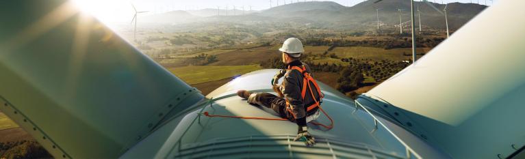 An apprentice sitting on top of a wind turbine
