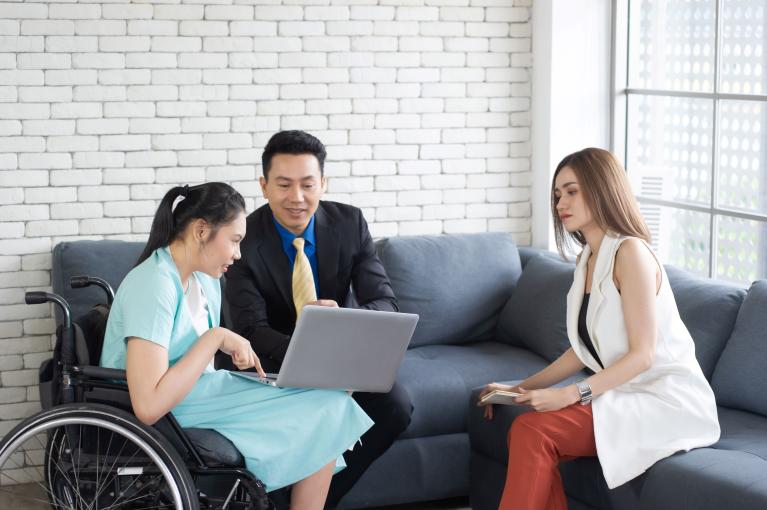 Female employee in a wheelchair talking with two other employees